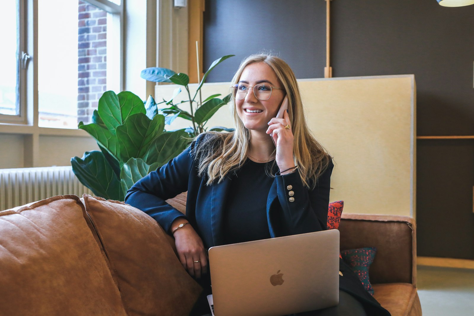 Smiling Hostigan support specialist taking a customer call with a laptop open